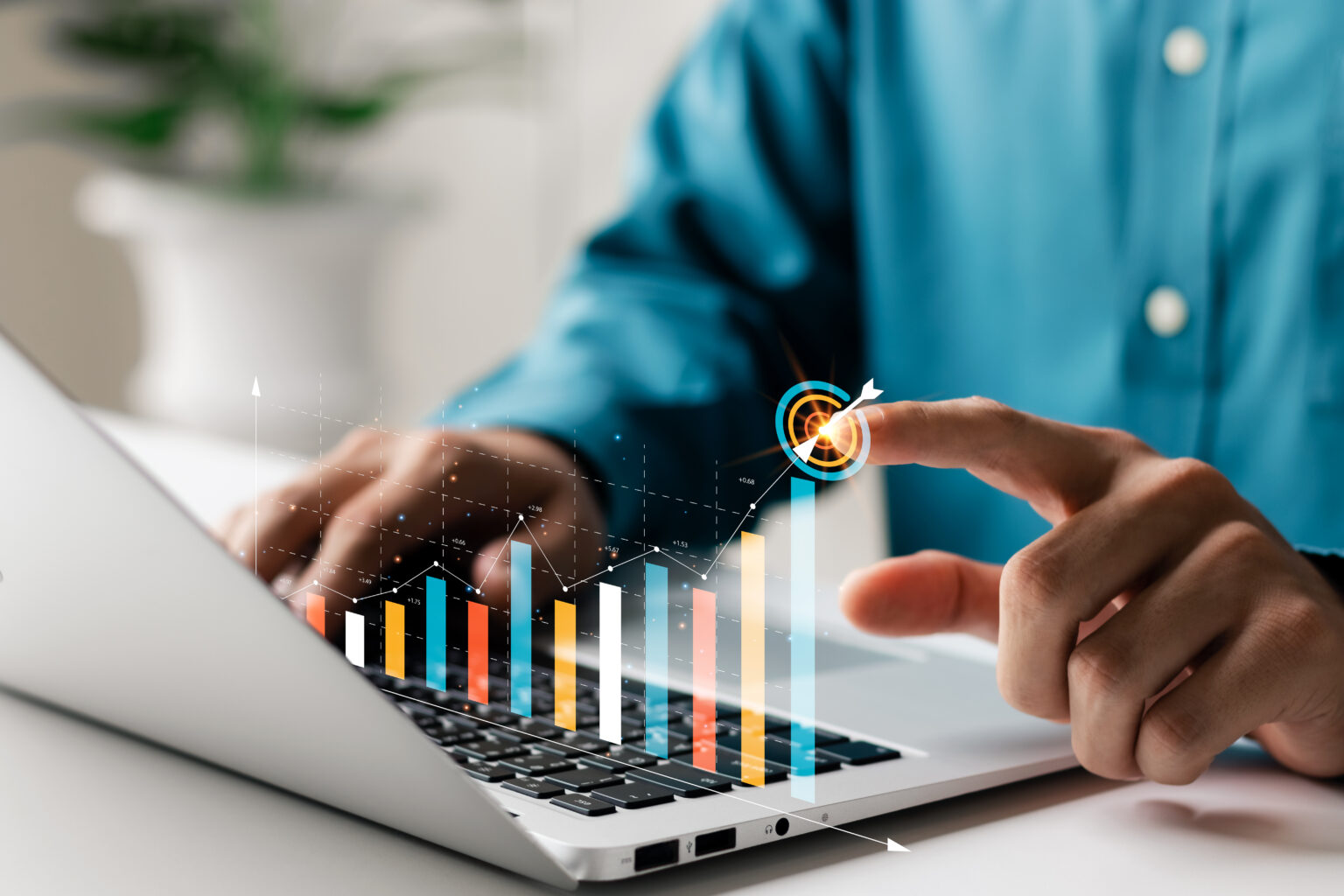 Back of a laptop and the hands of a man pointing towards the growth of some numbers on a graph.